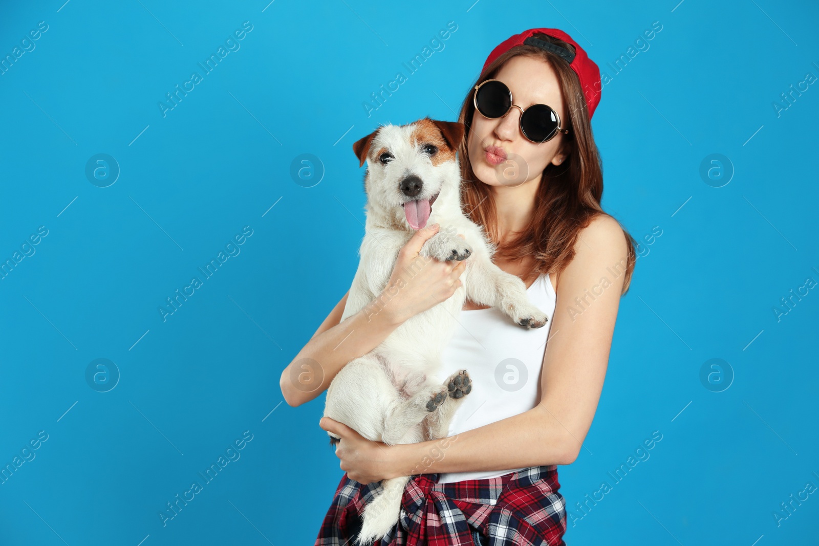 Photo of Young woman with her cute Jack Russell Terrier on light blue background. Lovely pet