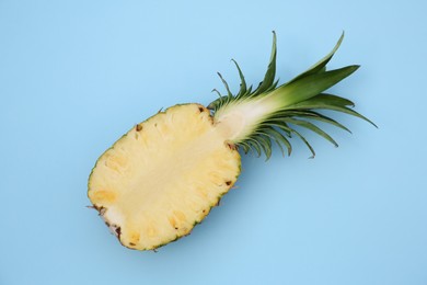 Half of ripe pineapple on light blue background, top view