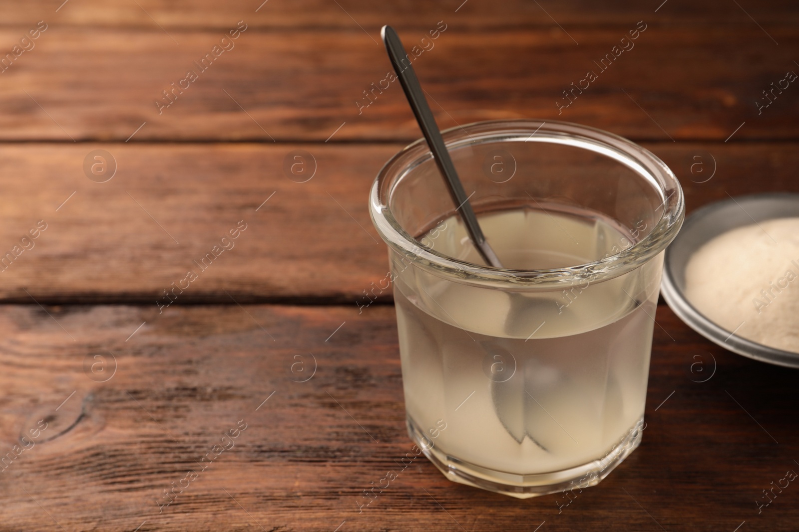 Photo of Glass of agar-agar jelly on wooden table. Space for text