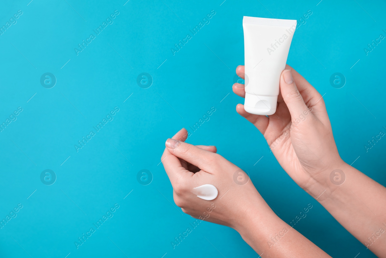 Photo of Woman with tube of hand cream on light blue background, closeup. Space for text