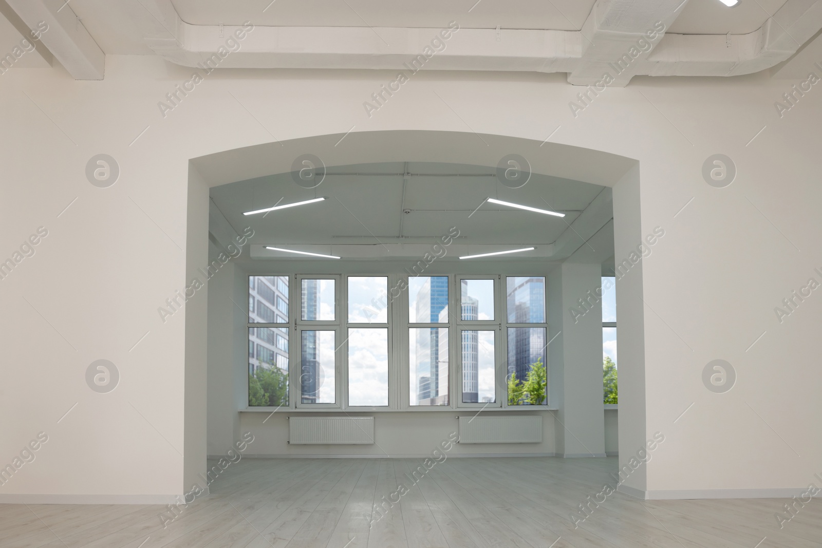 Photo of Empty office room with white walls, clean windows and modern lights on ceiling. Interior design