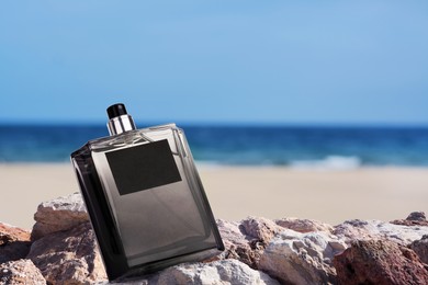 Image of Bottle of aquatic perfume on stones near ocean. Fresh sea breeze scent