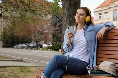 Photo of Woman listening to audiobook on bench outdoors