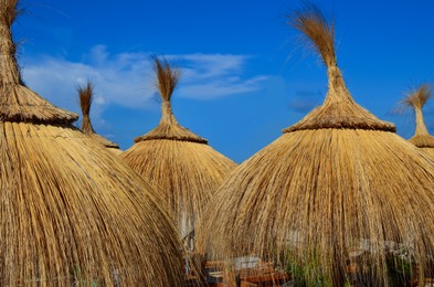 Beautiful straw beach umbrellas against blue sky