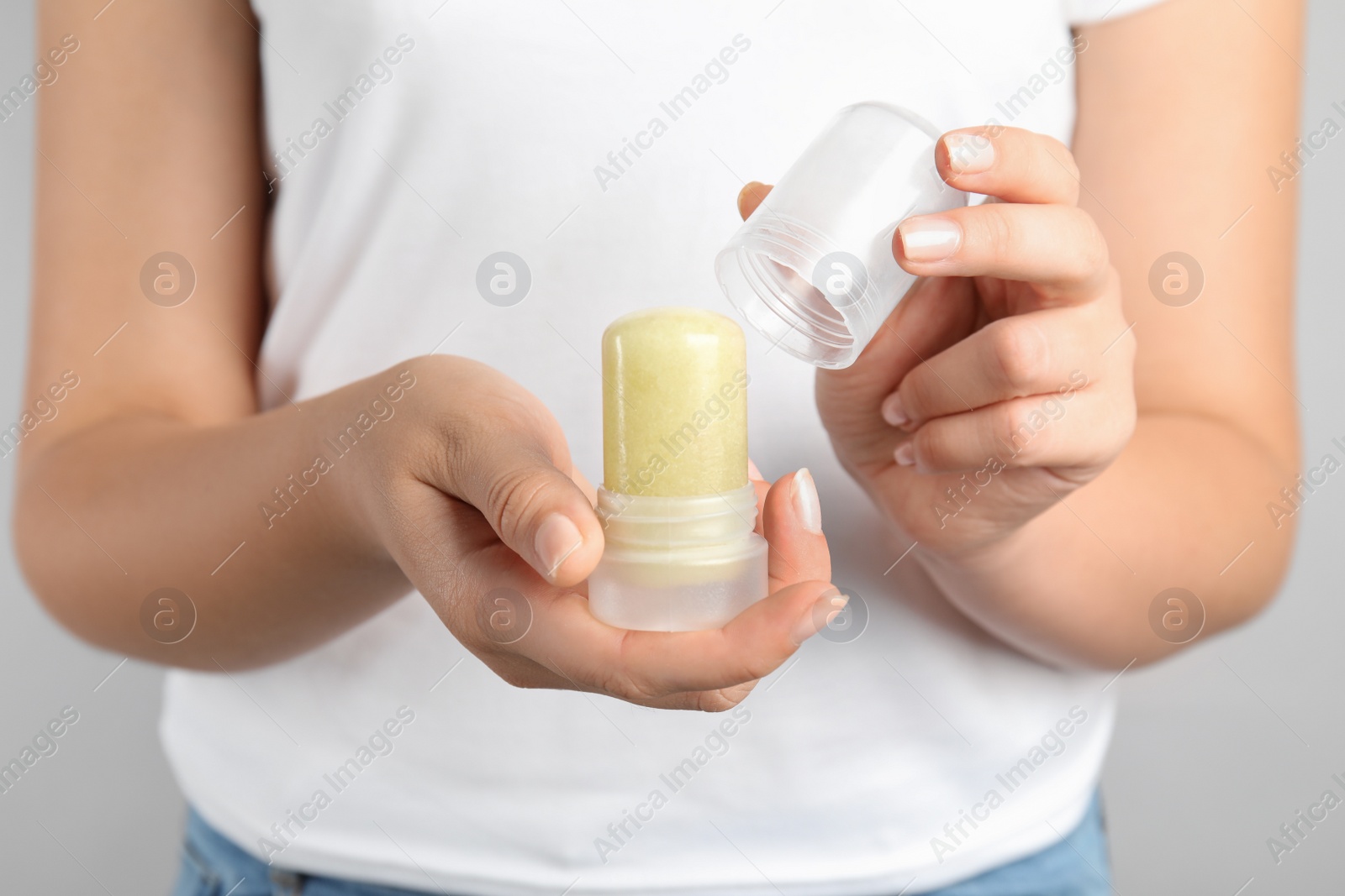 Photo of Young woman holding natural crystal alum stick deodorant, closeup