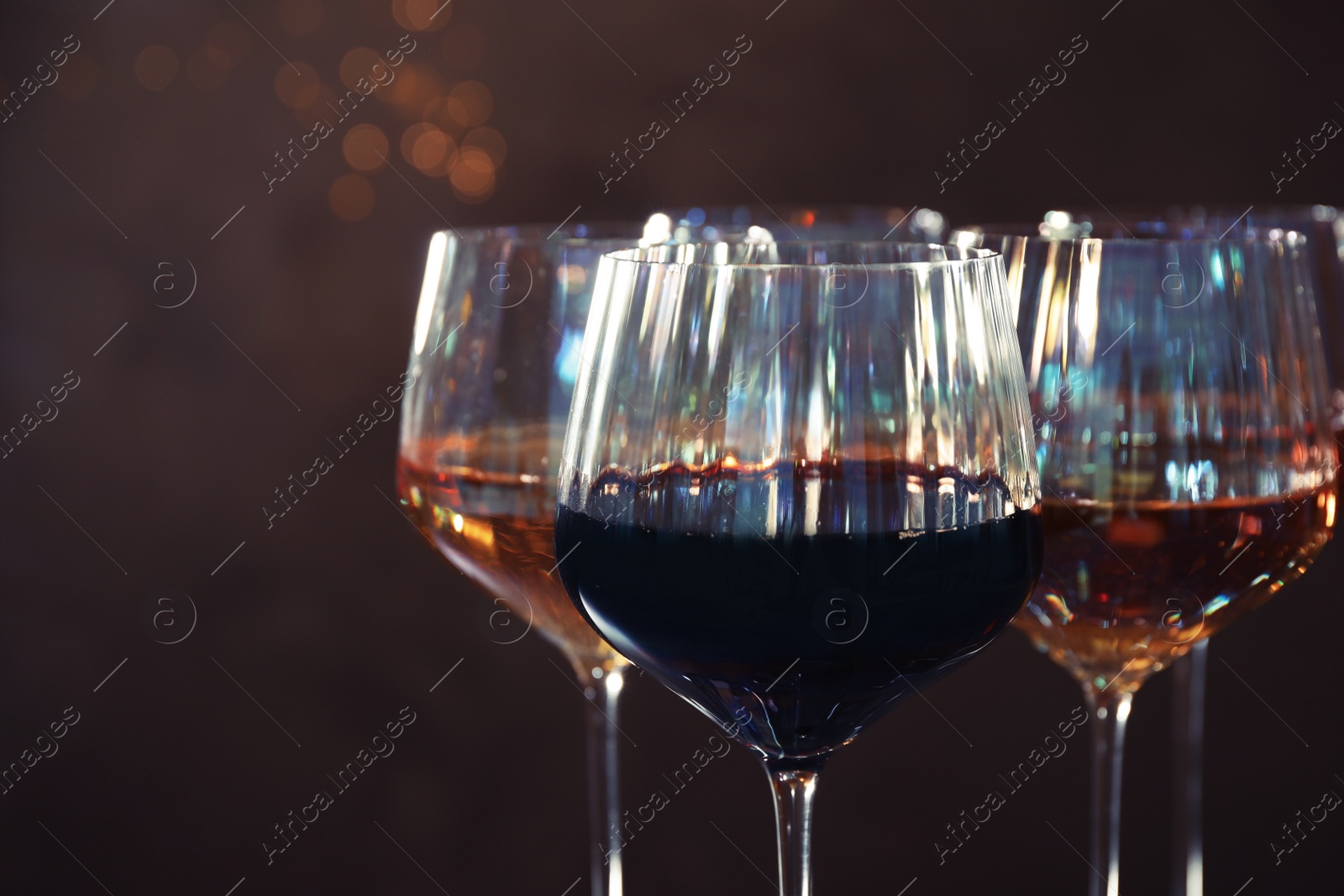 Photo of Elegant glasses with different wines on brown background, closeup