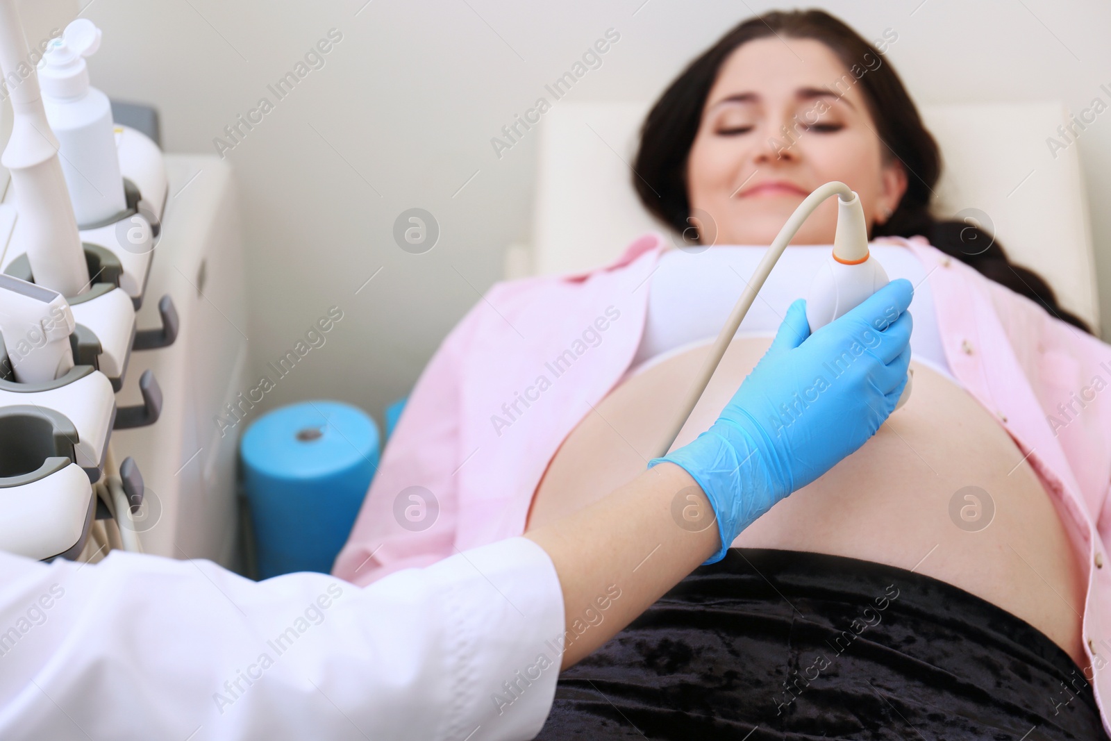 Photo of Young pregnant woman undergoing ultrasound scan in clinic