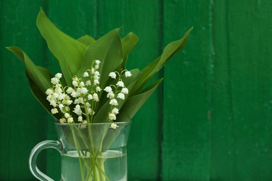 Photo of Beautiful lily of the valley flowers on green wooden background. Space for text