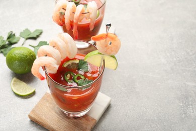 Tasty shrimp cocktail with sauce in glasses and lime on light grey table, closeup. Space for text