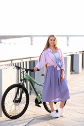 Photo of Young woman with bicycle in city on sunny day