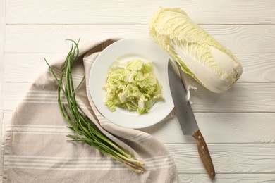 Photo of Fresh Chinese cabbage, green onion and knife on white wooden table, flat lay