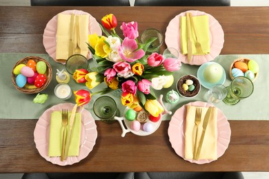 Festive Easter table setting with beautiful flowers and painted eggs, top view