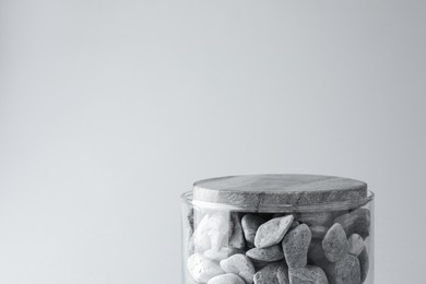 Photo of Presentation for product. Glass container with stones on light grey background. Space for text