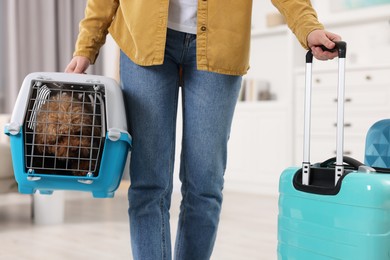 Travel with pet. Woman holding carrier with dog and suitcase at home, closeup