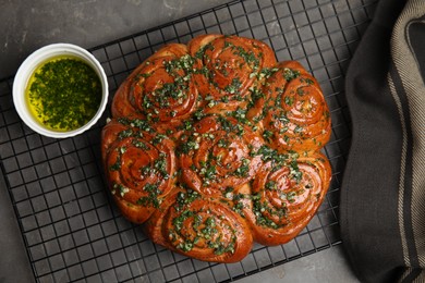 Photo of Traditional Ukrainian garlic bread with herbs (Pampushky) and aromatic oil on grey table, flat lay