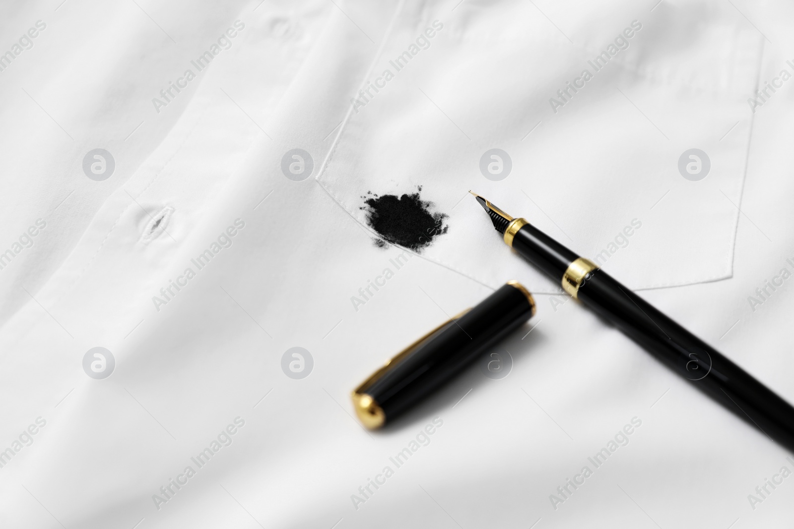 Photo of Pen and stain of black ink on white shirt, closeup. Space for text