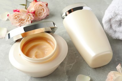 Photo of Hair care cosmetic products and flowers on light grey marble table
