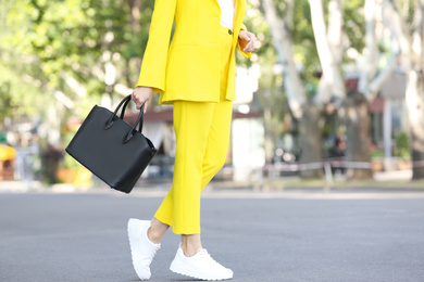 Photo of Young woman with stylish leather bag outdoors on summer day, closeup