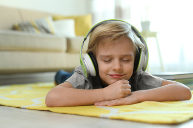 Photo of Cute little boy with headphones listening to audiobook at home