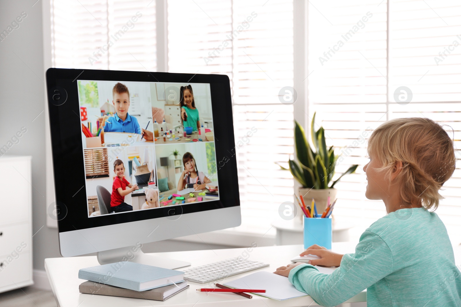 Photo of Little boy studying with classmates via video conference at home. Distance learning during COVID-19 pandemic