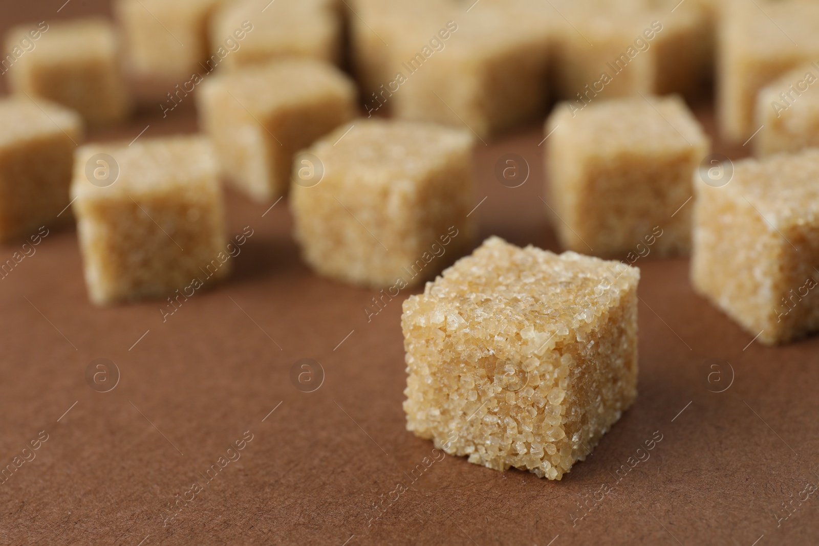 Photo of Brown sugar cubes on color background, closeup. Space for text