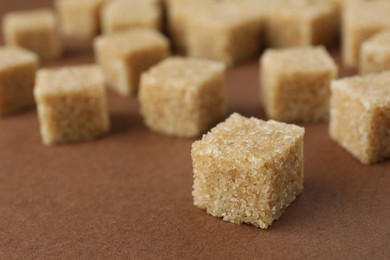 Brown sugar cubes on color background, closeup. Space for text