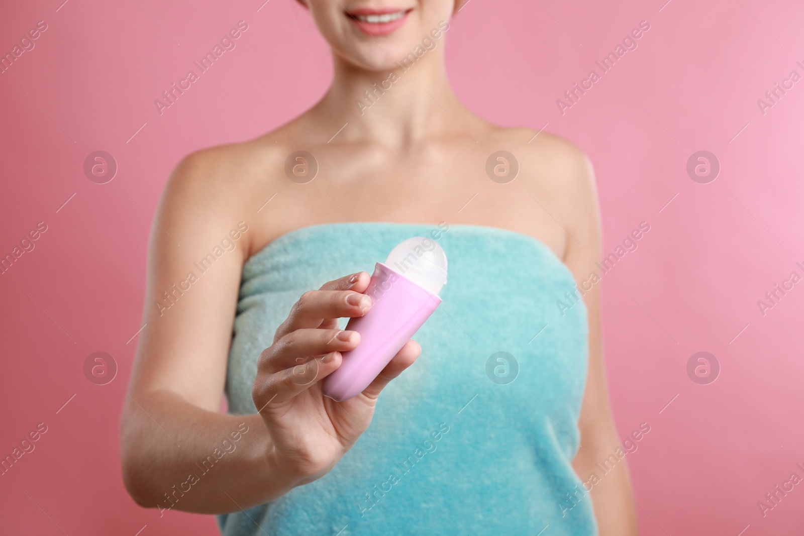 Photo of Young woman holding deodorant on pink background, closeup. Mockup for design