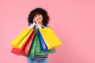 Photo of Happy young woman with shopping bags on pink background. Space for text