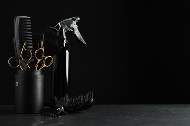 Photo of Different hairdresser tools on grey table against black background. Space for text