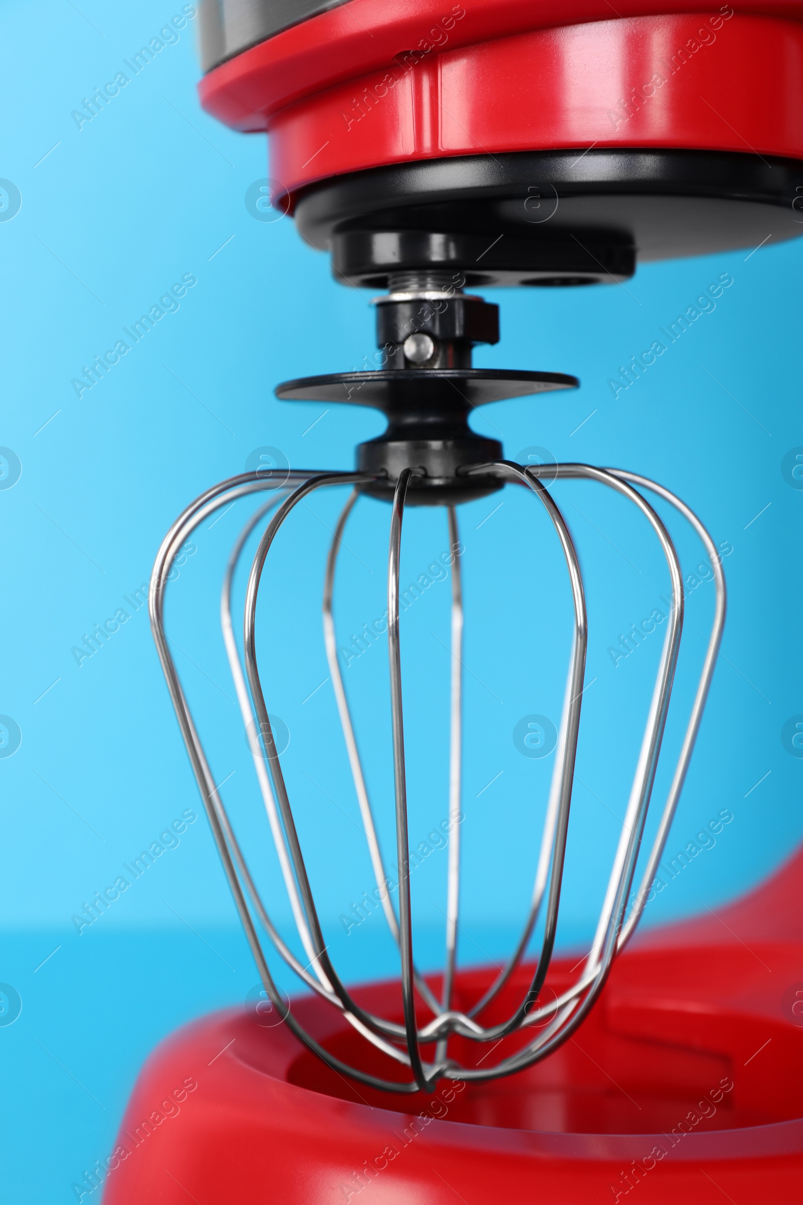 Photo of Closeup view of modern red stand mixer on turquoise background