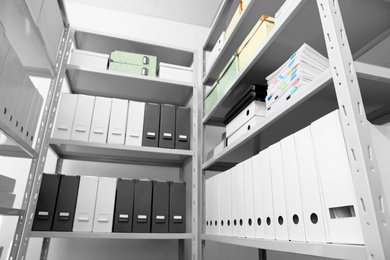 Folders and boxes with documents on shelves in archive, low angle view