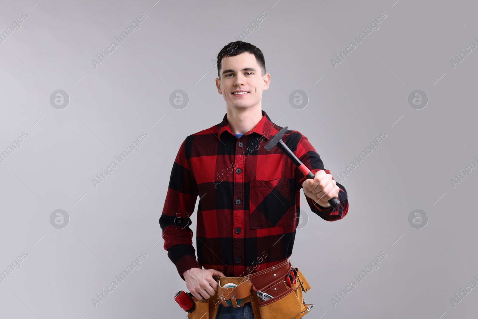 Photo of Professional repairman holding hammer on light grey background