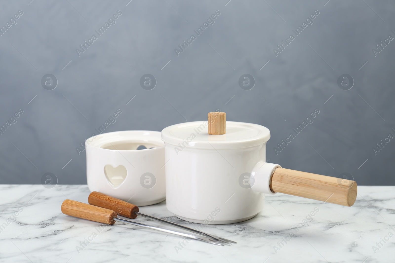 Photo of Fondue set on white marble table against light grey background