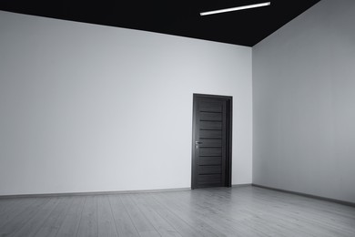 Photo of Empty renovated room with white walls and black door