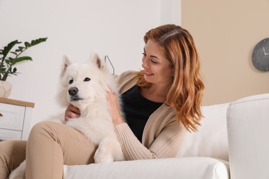 Photo of Beautiful woman with her dog sitting on sofa at home