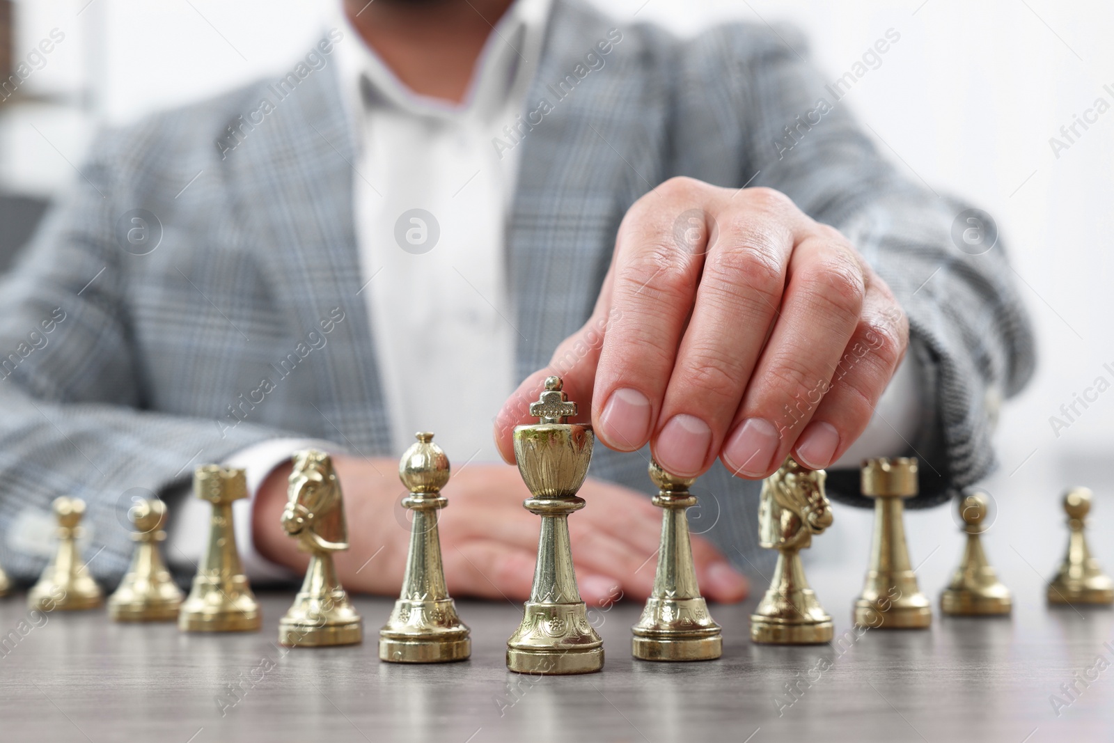 Photo of Man with chess pieces at wooden table indoors, closeup