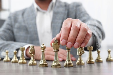 Photo of Man with chess pieces at wooden table indoors, closeup
