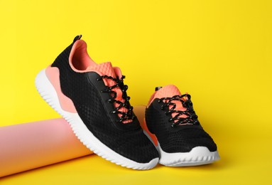 Pair of stylish sport shoes on yellow background