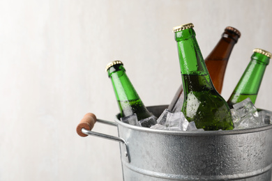 Photo of Metal bucket with bottles of beer and ice cubes on grey background