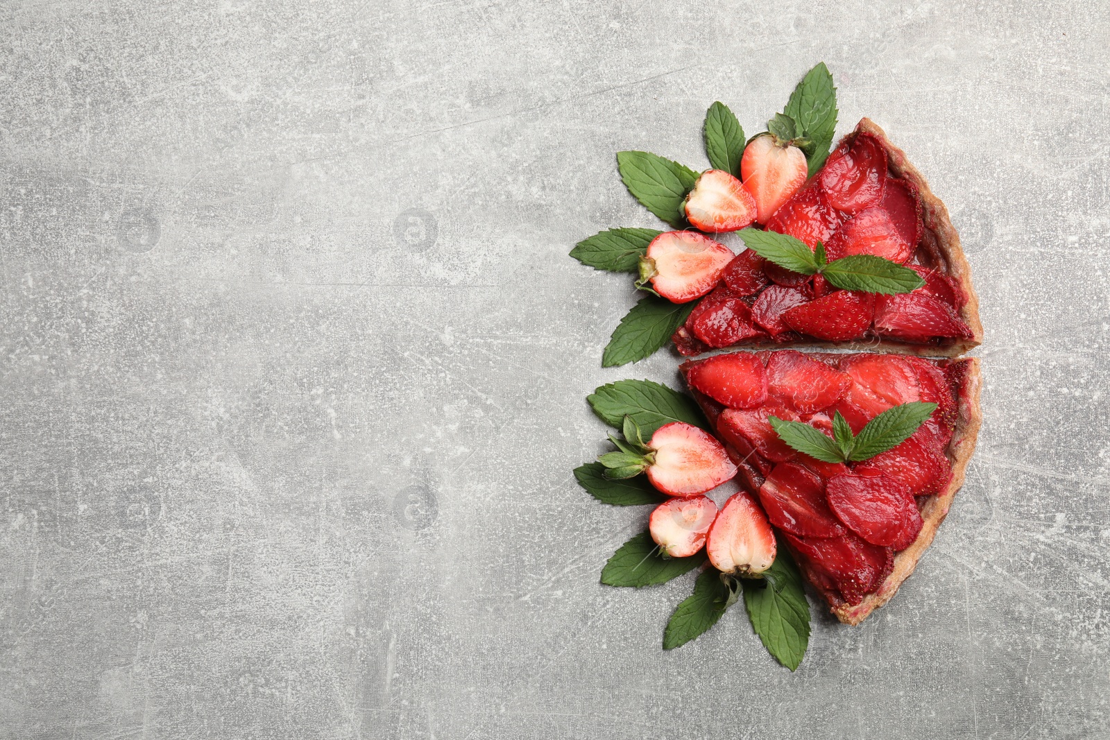 Photo of Pieces of delicious strawberry tart on light grey table, flat lay. Space for text