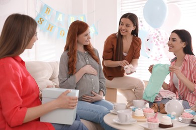 Happy pregnant woman spending time with friends at baby shower party