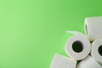 Photo of Soft toilet paper rolls on green background, flat lay. Space for text