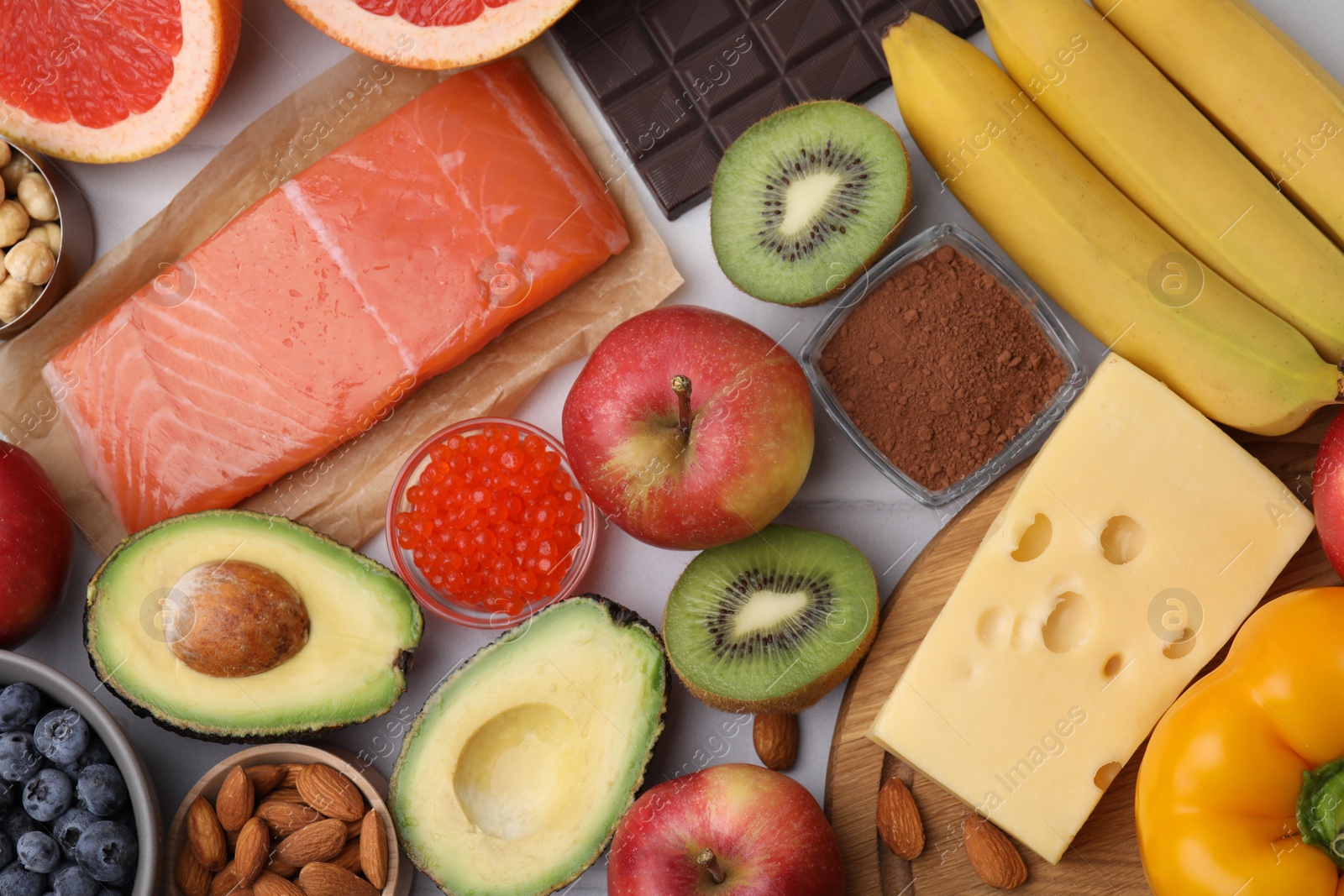 Photo of Many different products on white tiled table, flat lay. Natural sources of serotonin