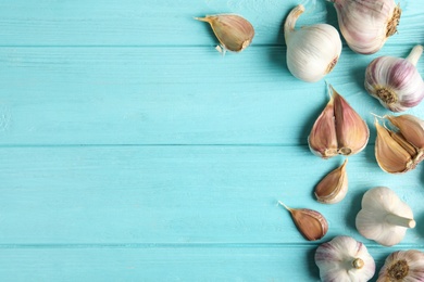 Photo of Fresh unpeeled garlic bulbs and cloves on light blue wooden table, flat lay with space for text. Organic product