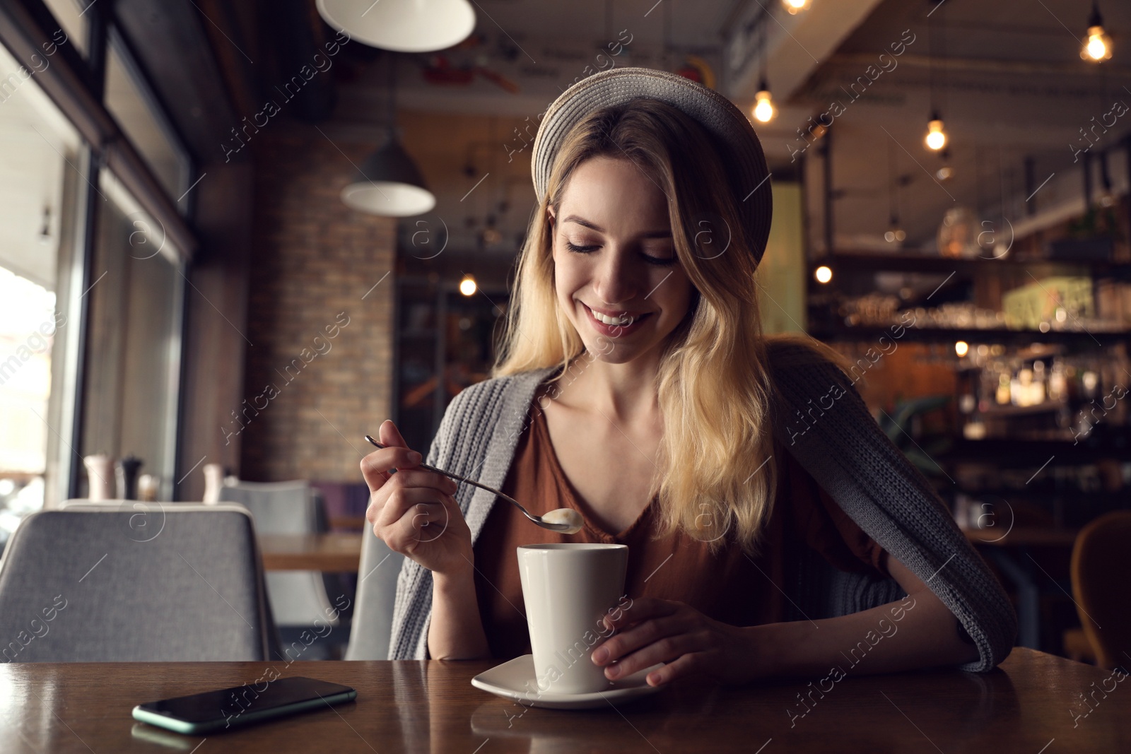 Photo of Young woman with cup of coffee at cafe in morning