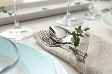 Photo of Elegant cutlery with green leaves on table, closeup. Festive setting