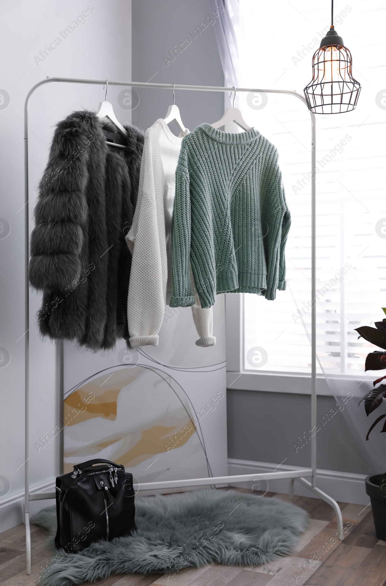 Photo of Stylish warm clothes on rack in dressing room interior