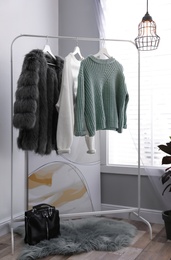 Stylish warm clothes on rack in dressing room interior