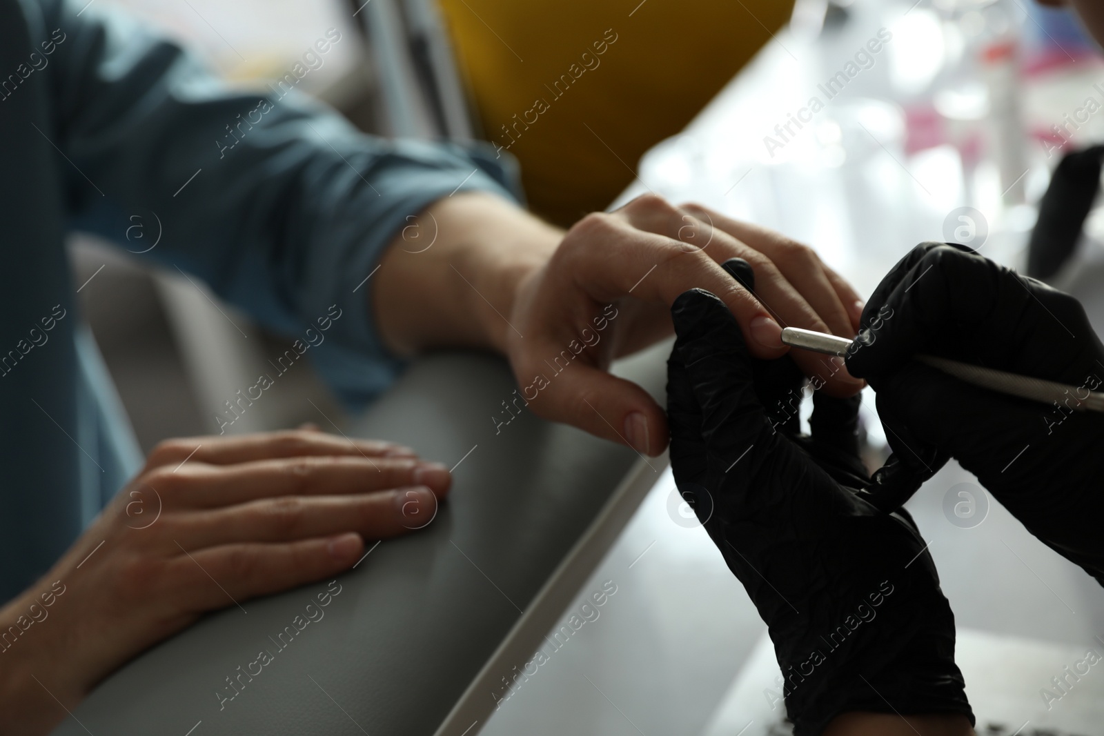 Photo of Professional manicurist working with client in beauty salon, closeup