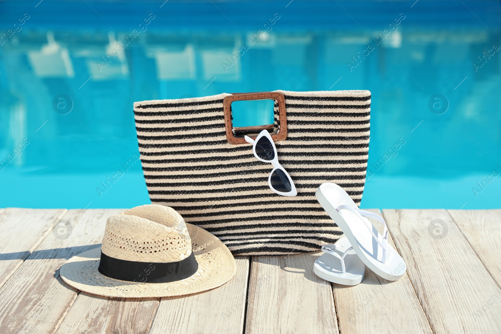 Photo of Beach accessories on wooden deck near outdoor swimming pool